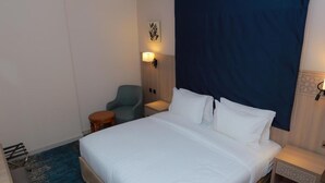 Een hotelkamer met een groot bed, een bureau, een stoel en een aan de muur bevestigd telefoon.