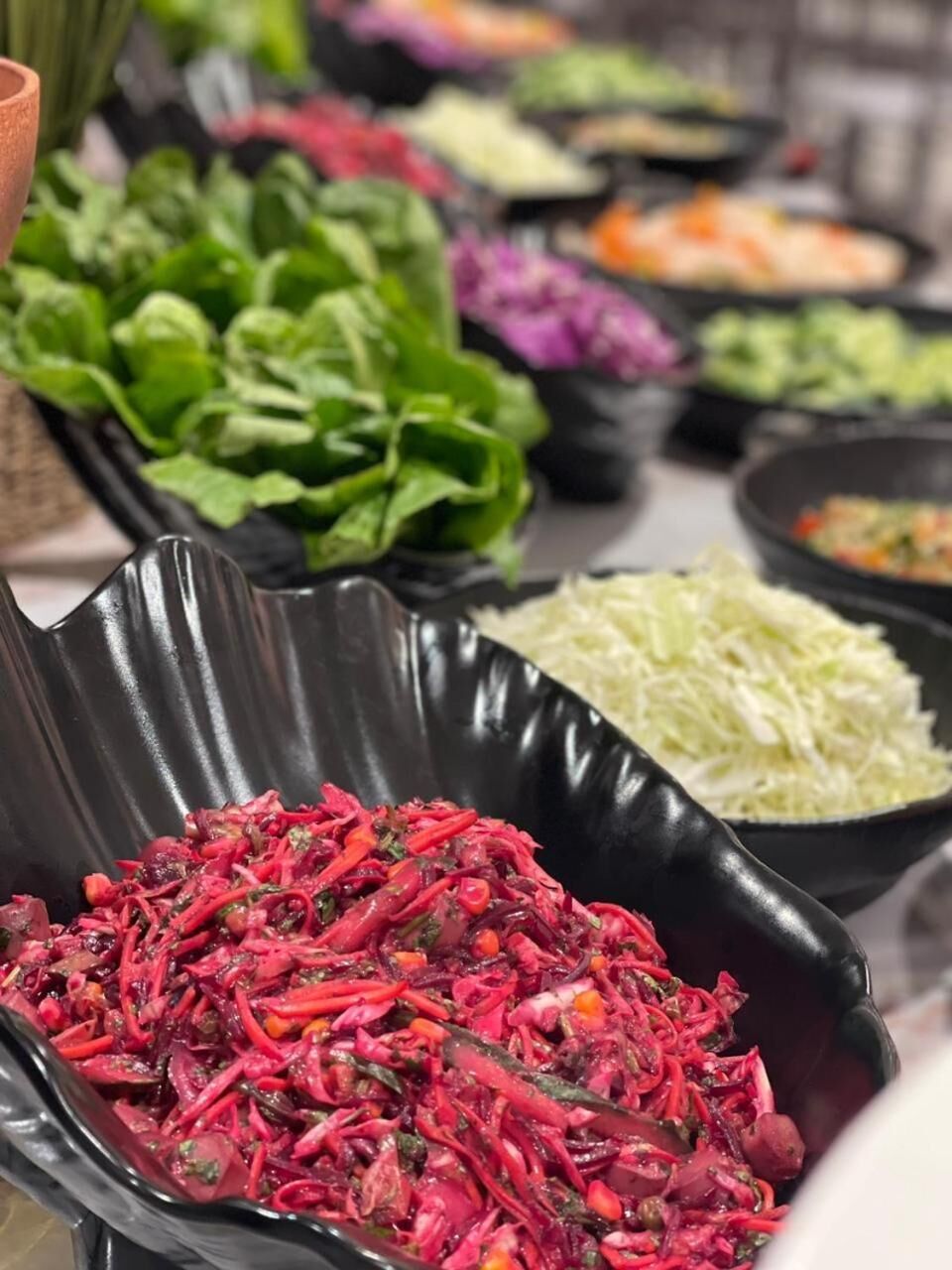 A variety of prepared salads in black bowls.