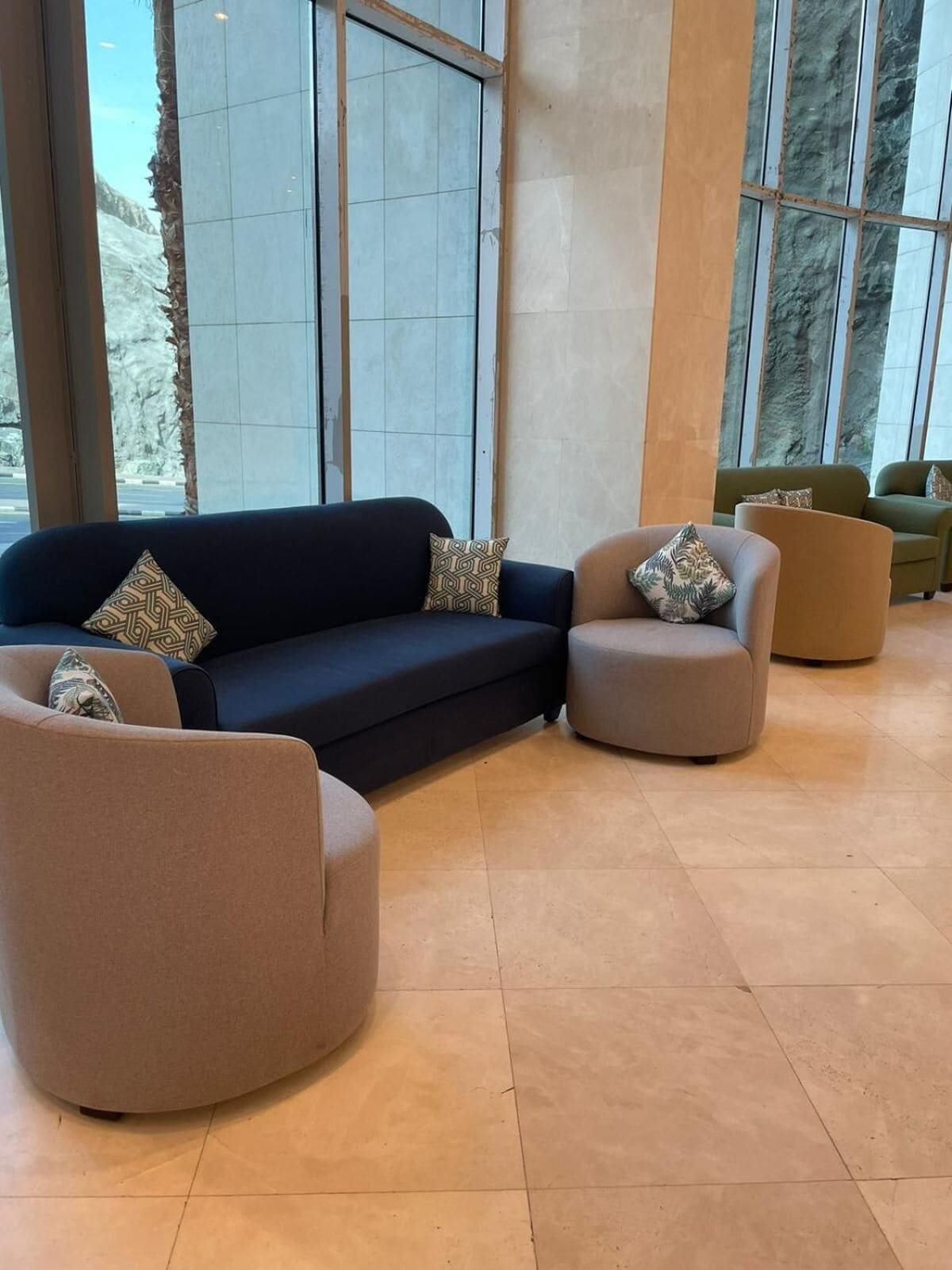 Un intérieur moderne avec un canapé bleu foncé, deux fauteuils et un ensemble de canapés verts.