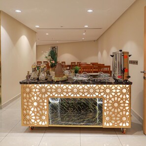 Habitación de hotel con una encimera central tipo isla, una cafetera y una planta decorativa.