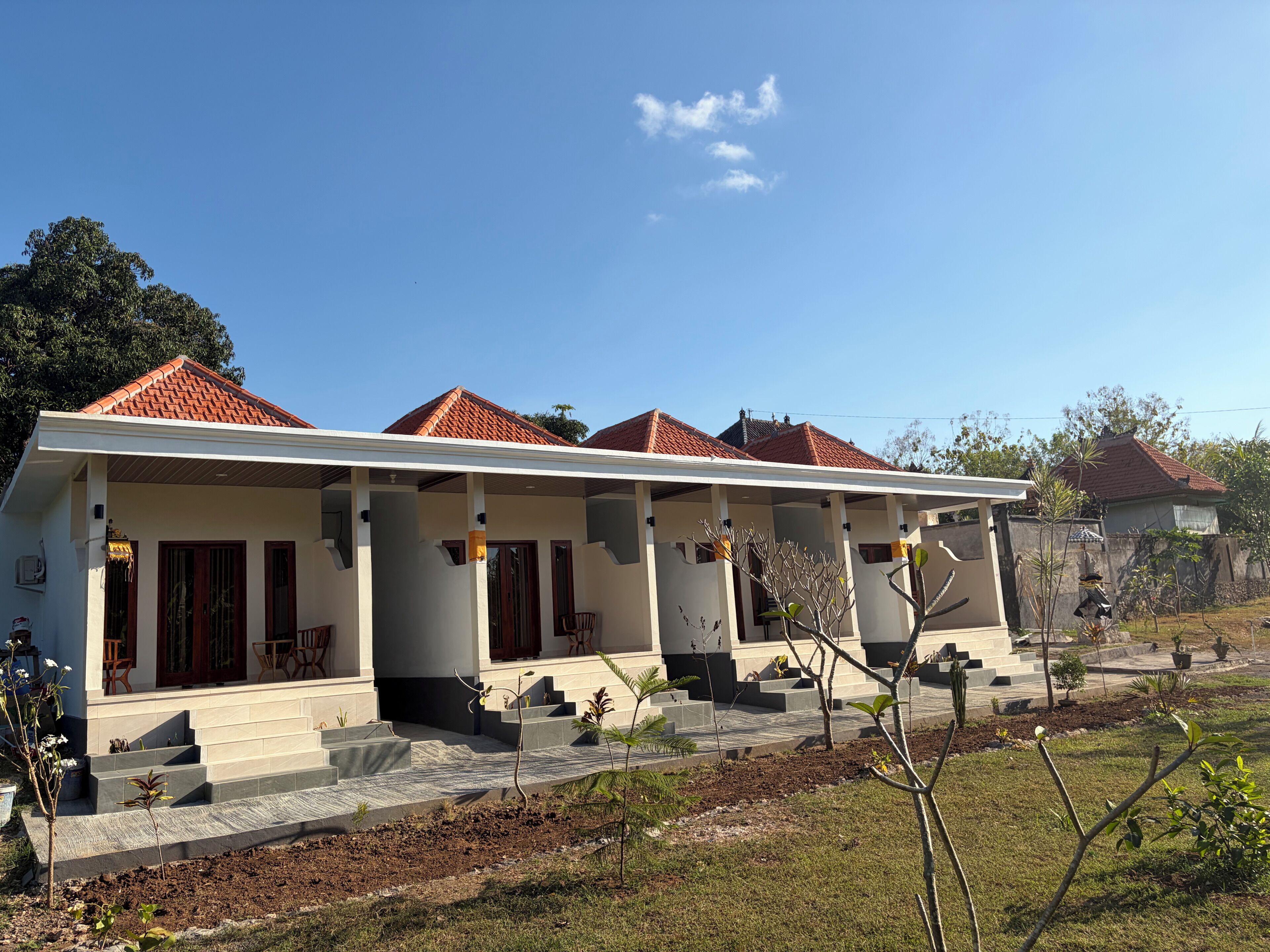 A two-story house with a covered porch, a tiled roof, and a landscaped garden.
