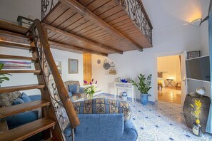 A spacious living area with a wooden staircase, a blue sofa, and a tiled floor. - Villa Bellora: A welcoming independent house situated at a short distance from the beach, with Free WI-FI. (Praiano)
