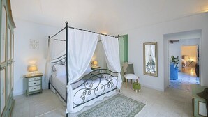 Un lit à baldaquin, avec des tables de chevet, une chaise et un tableau encadré accroché au mur.