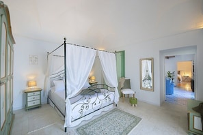 A four-poster bed with a canopy, bedside tables, a chair, and a framed picture on the wall. - Villa Bellora: A welcoming independent house situated at a short distance from the beach, with Free WI-FI. (Praiano)