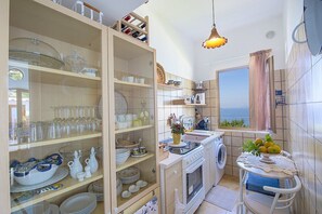 A compact kitchen with a view, featuring a stove, sink, and a window overlooking the sea. - Villa Bellora: A welcoming independent house situated at a short distance from the beach, with Free WI-FI. (Praiano)