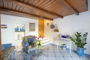 A room with a wooden ceiling, patterned floor, a sofa, a table with decorative items, and a potted plant. - Villa Bellora: A welcoming independent house situated at a short distance from the beach, with Free WI-FI. (Praiano)