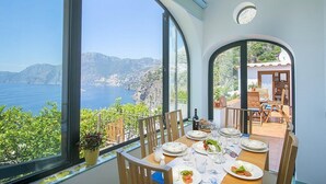 Un coin repas avec une table dressée pour quatre personnes, offrant une vue panoramique sur la côte.