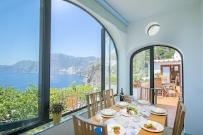A dining area with a table set for four, overlooking a scenic coastal view. - Villa Bellora: A welcoming independent house situated at a short distance from the beach, with Free WI-FI. (Praiano)