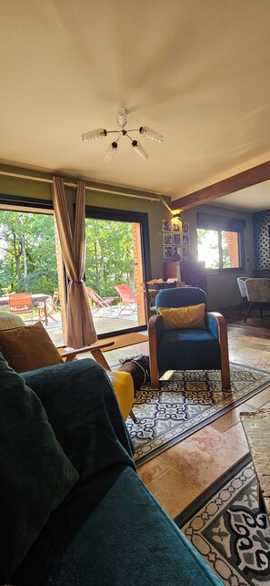 A spacious living room with a large window, a ceiling fan, and a patterned rug. - A charming home in the heart of the Perche region, blending nature, elegance, and authenticity. (Arcisses)