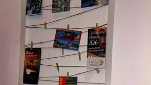Un panneau d’affichage où sont accrochées diverses brochures de voyage et des cartes postales.
