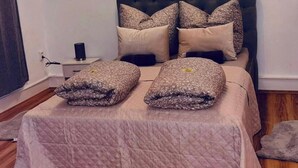 Une chambre à coucher avec un lit, des oreillers, une table de chevet et un tapis.