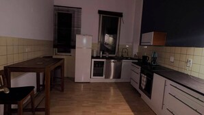 Une cuisine compacte comprenant une table à manger, un réfrigérateur, un four à micro-ondes et un évier.