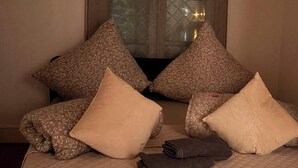 Un lit avec une couverture matelassée, plusieurs oreillers et une serviette pliée.