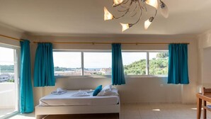 Ein Schlafzimmer mit Bett, Vorhängen, Blick ins Freie und einer Kristallleuchter.