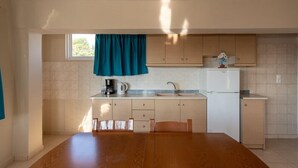 Eine Küche mit Holztisch, Schränken, Spüle und einem Fenster mit Vorhang.