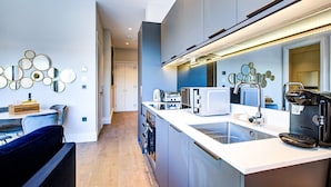 A modern kitchen with a central island, built-in appliances, and a decorative wall mirror. - Hybridresi Canary Wharf (London)
