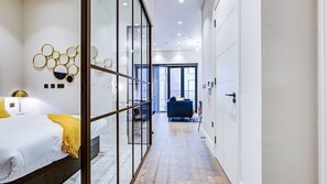 Habitación de hotel moderna con cama, separador de vidrio, sofá azul y vistas a través del cristal.