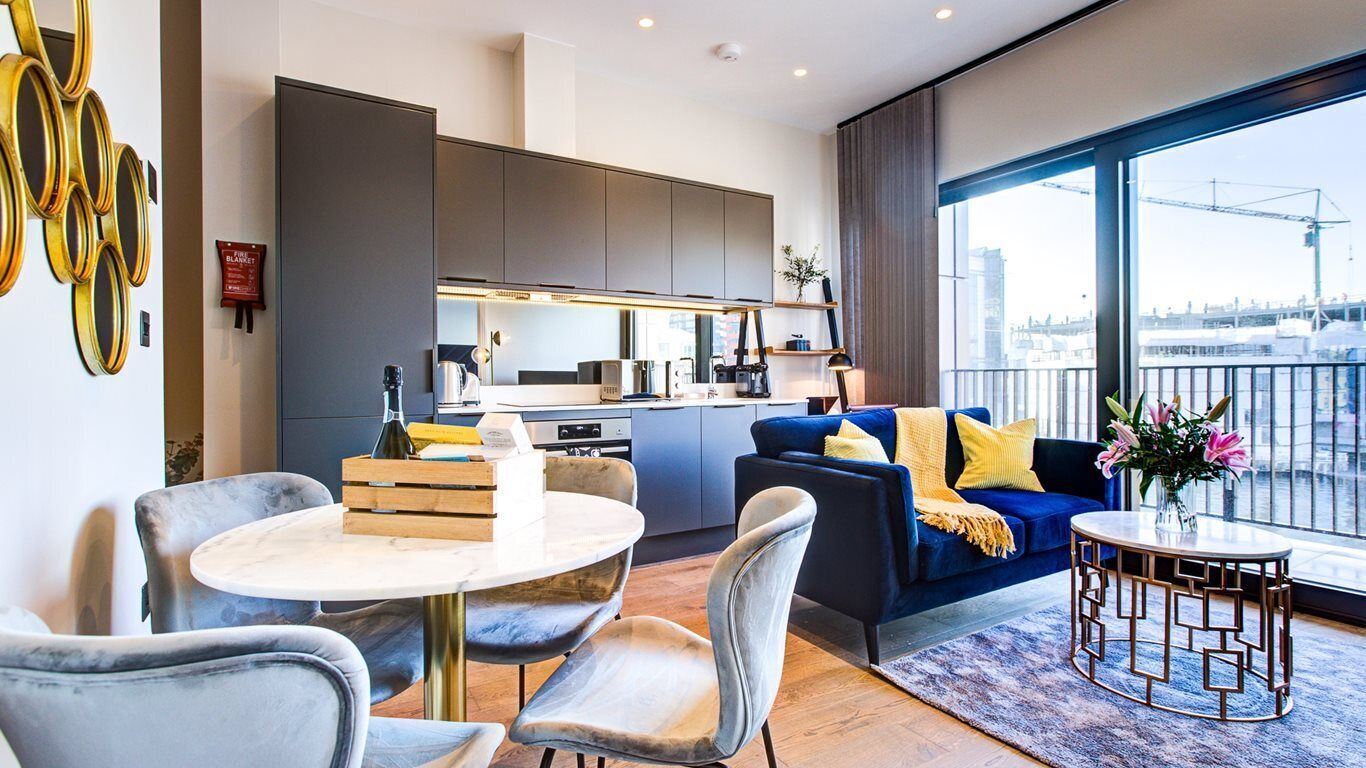 A modern living room with a sofa, a coffee table, and a dining area with chairs.