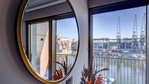 A room with a large window overlooking a marina with boats and cranes. - Hybridresi Canary Wharf (London)