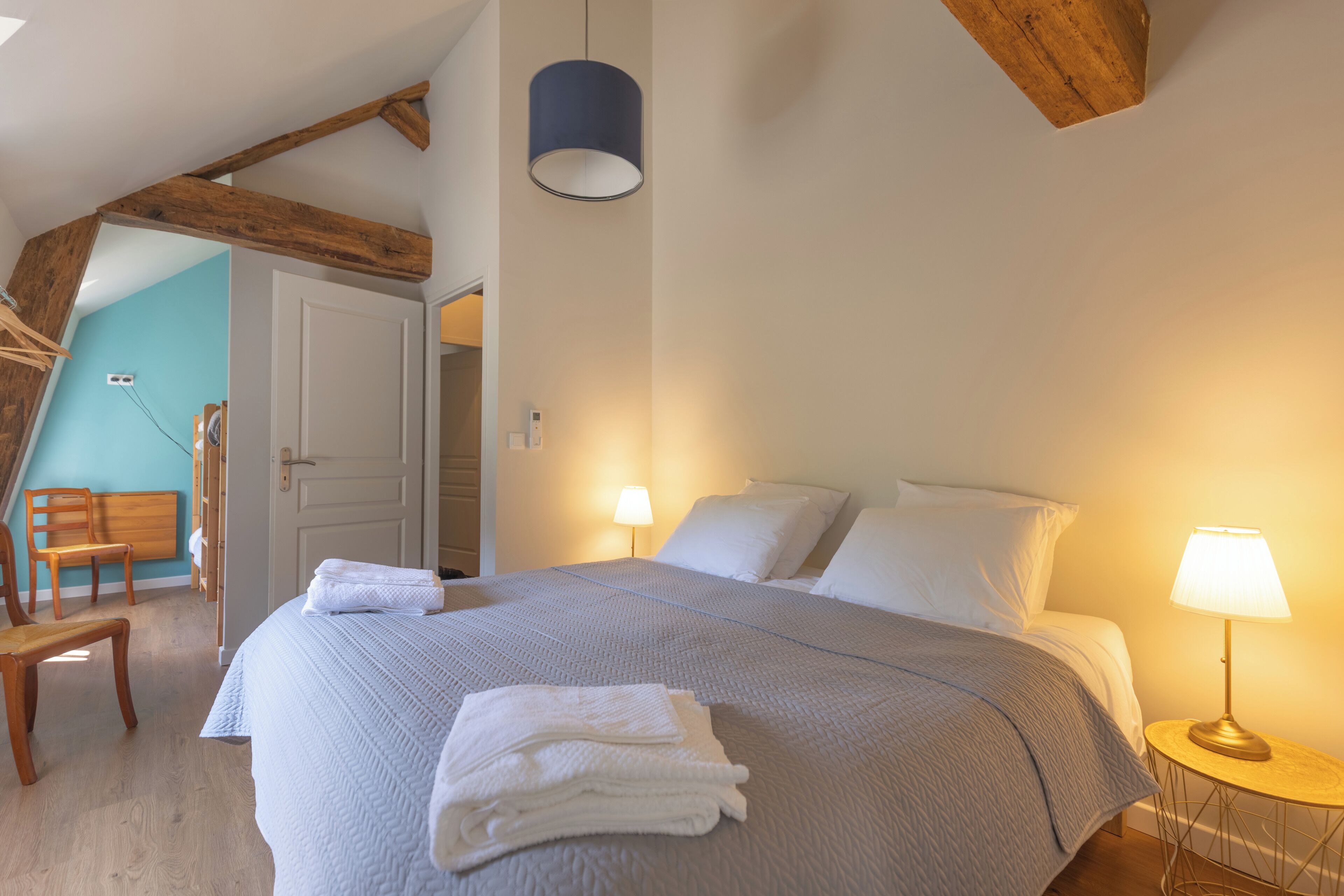 Une chambre à coucher avec un grand lit, une lampe de chevet et une chaise en bois.