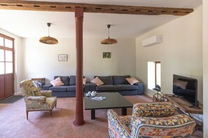 Una sala de estar con un juego de sofá, una mesita de centro, un sillón estampado y un televisor.