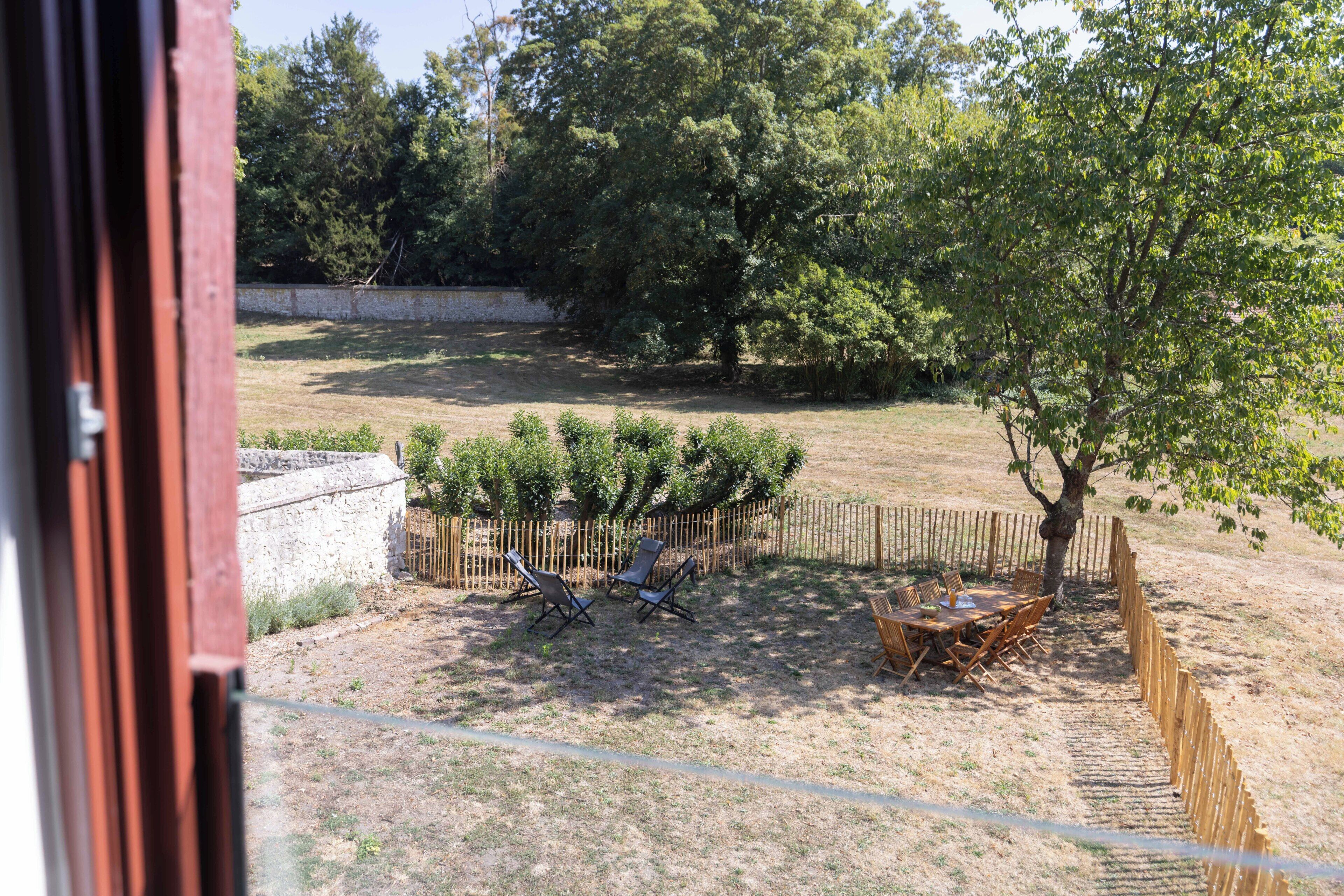A backyard with a wooden fence, a table with chairs, and a tree.