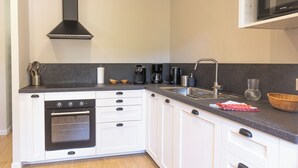 A modern kitchen with white cabinetry, a black range hood, a built-in oven, a coffee maker, and a microwave. - The Steward's House in Logempré—23 ha of parkland, a river, and a padel court (Pont-Saint-Pierre)