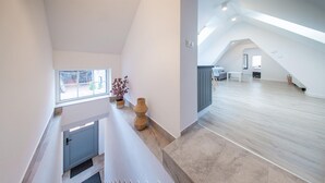 A spacious loft with a high ceiling, a staircase, and a view of the outdoors.