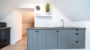A kitchen with grey cabinets, a sink, and a microwave.