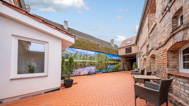 A courtyard with a mural, outdoor seating, and a brick building.