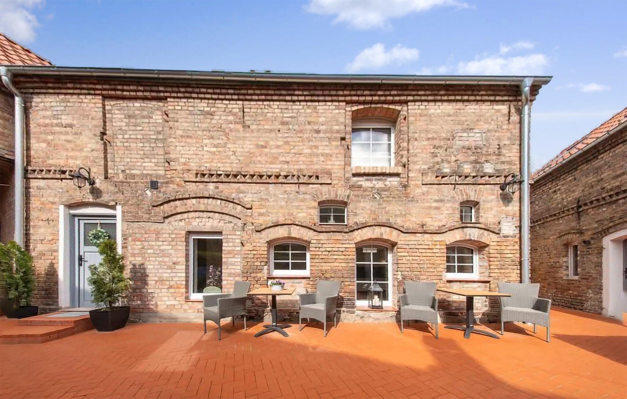 A brick building with a courtyard, outdoor seating, and a door.