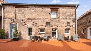 A brick building with a courtyard, outdoor seating, and a door.