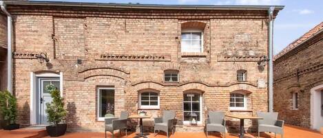 A brick building with a courtyard, outdoor seating, and a door.