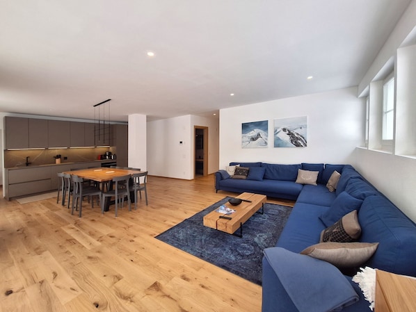 A modern living space with a kitchen, dining area, and a large blue sofa. - Silberdistel EG by Interhome (Saas-Fee)