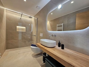 A modern bathroom with a glass-enclosed shower, a white sink, and a wooden vanity. - Silberdistel EG by Interhome (Saas-Fee)
