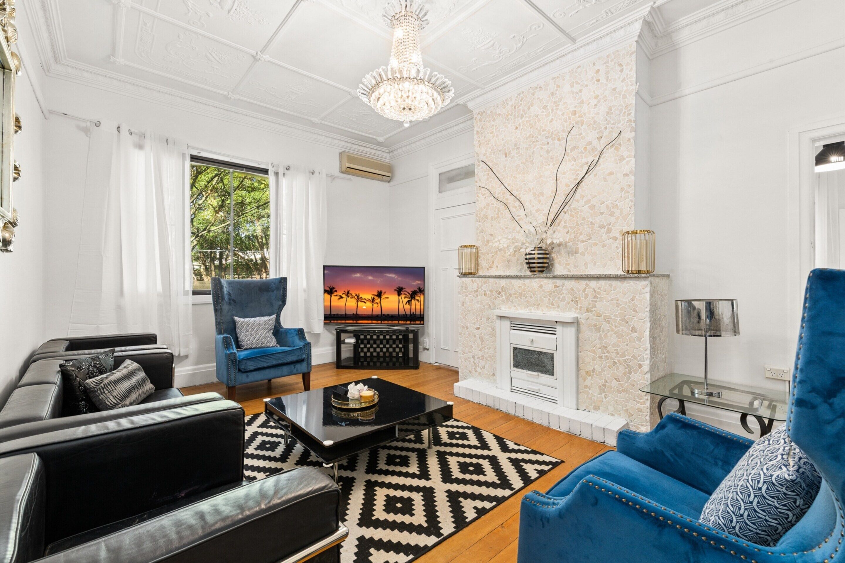 A living room with a fireplace, a television, and a blue armchair.