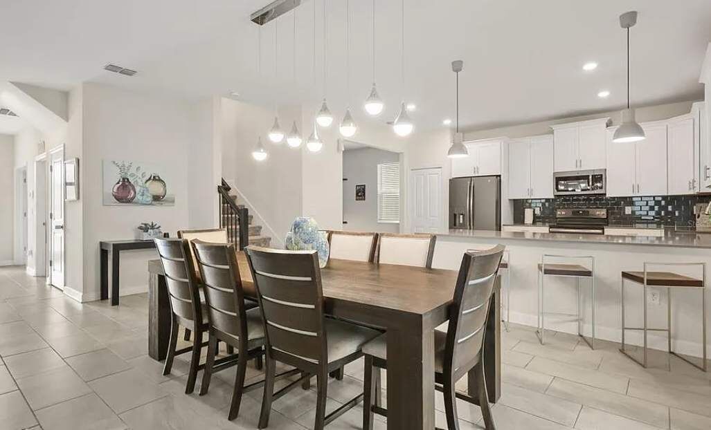 A modern kitchen with white cabinets, a central island, and pendant lighting.