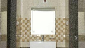 Un baño con lavamanos, espejo y paredes de azulejos.