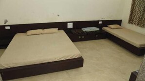 Una habitación con una cama grande, una cama más pequeña y un banco.