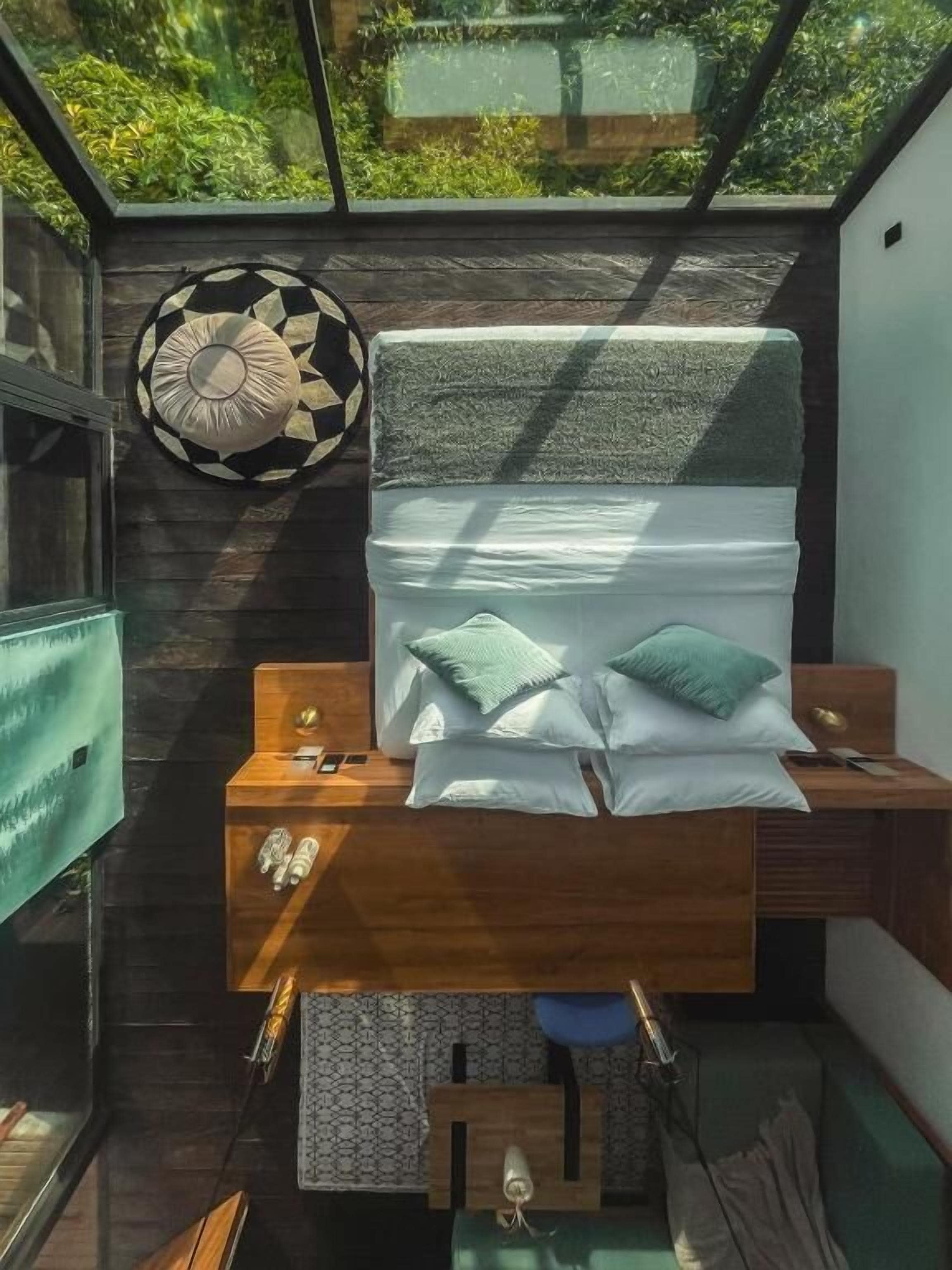 A compact bedroom with a bed, bedside tables, and a hanging light fixture.