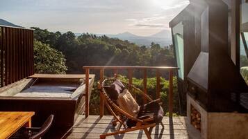 A wooden deck with a hot tub, a wooden table, and a chair with cushions.