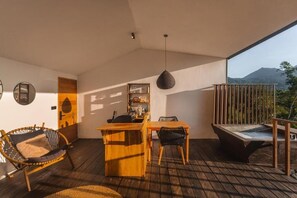 A wooden deck with a dining area, a hanging light fixture, and a view of a mountain.