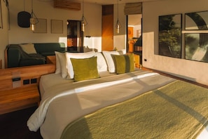 Una habitación de hotel moderna con una cama grande, un sofá verde y una mesita de noche de madera.
