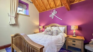 Una camera da letto con un letto in legno, una parete viola e un libellula decorativa.