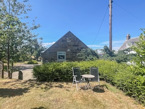 A stone building with a triangular roof, a framed picture, and a small table with chairs in front. - Stable Cottage - UK52294 (Fylingdales)