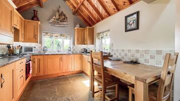 A kitchen with wooden cabinets, a stone floor, and a dining area with a table and chairs.