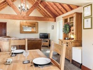 A dining area with a wooden table, chairs, and a television. - Stable Cottage - UK52294 (Fylingdales)