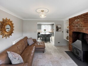 A living room with a leather sofa, a fireplace, and a kitchen in the background. - 2 bedroom accommodation in Hamsterley, near Bishop Auckland (Hamsterley, near Bishop Auckland)
