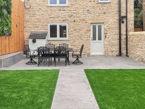 A stone building with a patio, a dining table with chairs, and a door. - 2 bedroom accommodation in Hamsterley, near Bishop Auckland (Hamsterley, near Bishop Auckland)