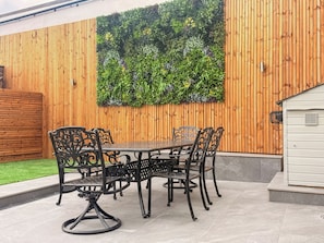 A patio area with a wooden fence, a table with chairs, and a vertical garden. - 2 bedroom accommodation in Hamsterley, near Bishop Auckland (Hamsterley, near Bishop Auckland)